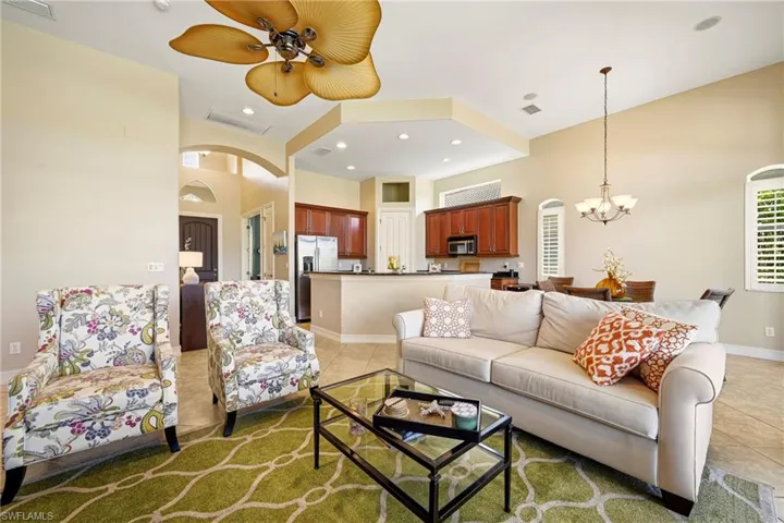 Living area with arched walkways, a high ceiling, light tile patterned flooring, a ceiling fan, and suspended lighting