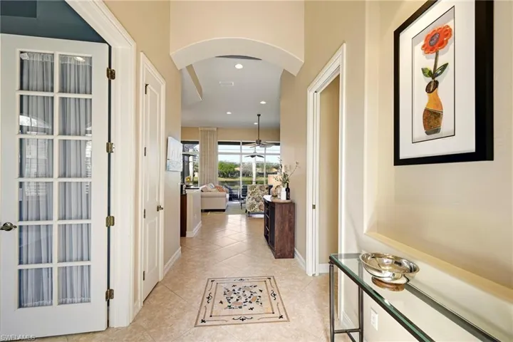 Hallway with arched walkways, recessed lighting, and light tile patterned flooring