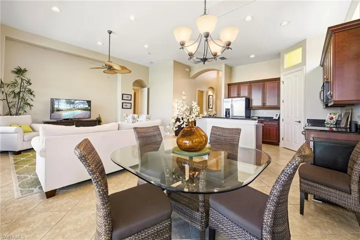 Dining room with hanging lights, arched walkways, light tile patterned floors, and ceiling fan