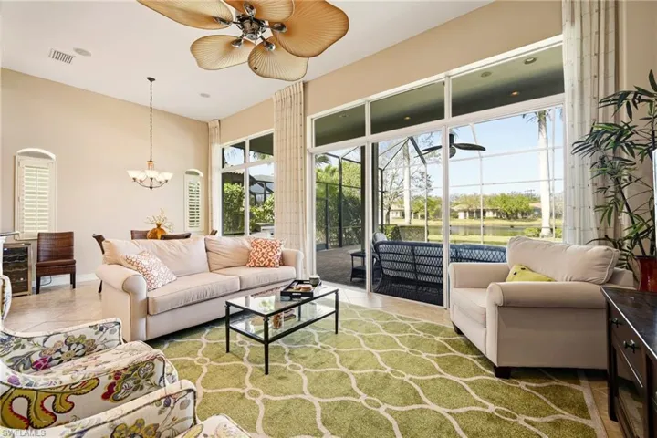Living room featuring a sunroom, tile patterned floors, hanging lights, ceiling fan, and a high ceiling