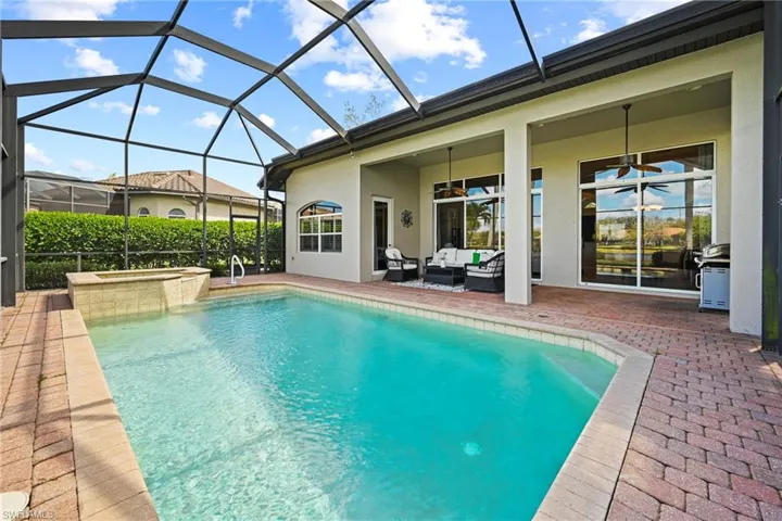 Relaxing pool / spa with a sunroom, a patio, a lanai, an outdoor hangout area, and area for grilling