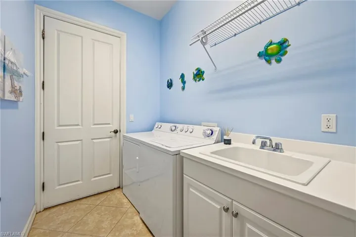 Laundry room featuring light tile patterned floors and washer and clothes dryer