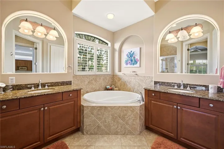 Bathroom with a bath, two vanities, a shower stall, and light tile patterned floors