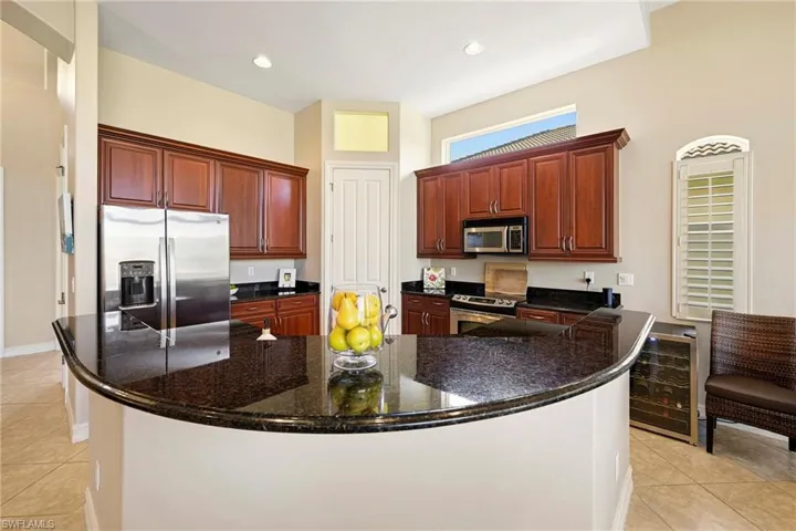 Kitchen with light tile patterned flooring, stainless steel appliances, dark stone countertops, a large island, and recessed lighting