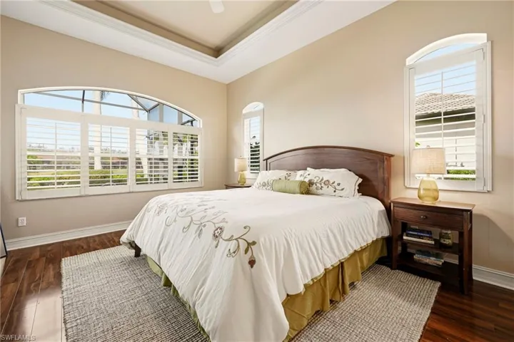 Bedroom featuring dark wood-style floors, ornamental molding, a raised ceiling, and ceiling fan