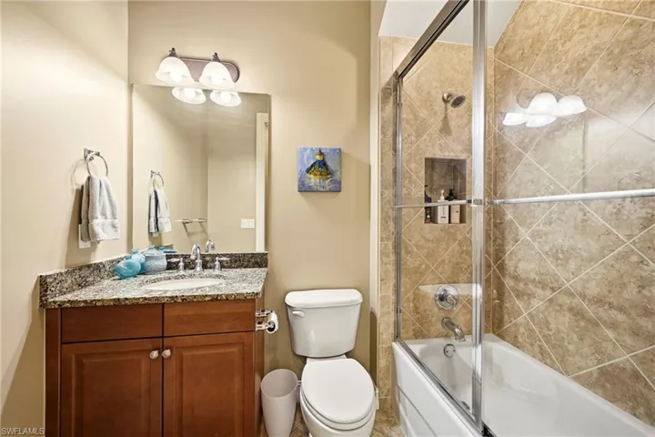 Bathroom featuring vanity and bath / shower combo with glass door