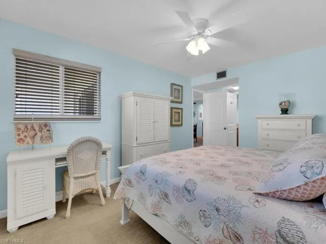 Carpeted bedroom with ceiling fan and an office area