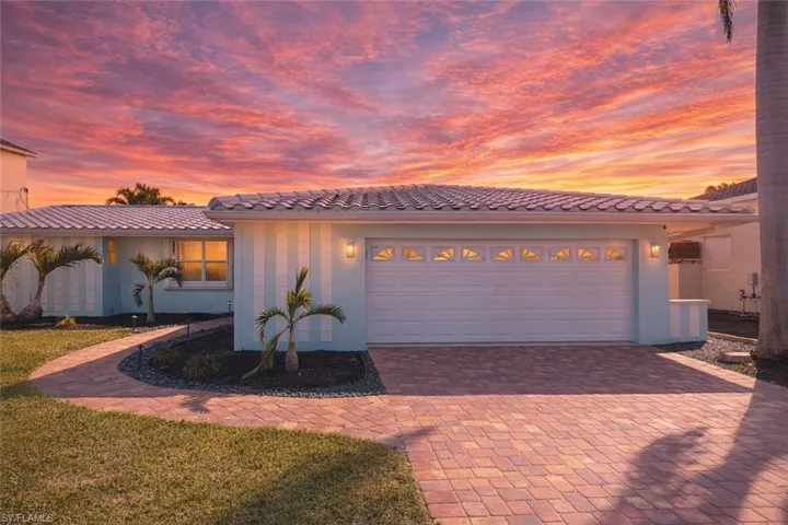 Exterior showcasing a tile roof, light blue siding with vertical white accents, and a two-car garage with transom windows