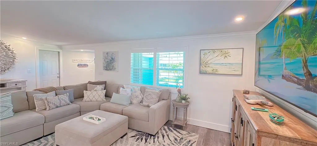 Open living area featuring wood-finish flooring, white walls, and crown molding