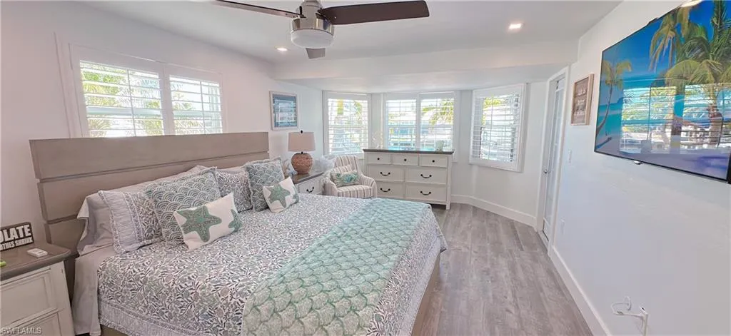 Spacious room featuring wood-finish flooring, a contemporary ceiling fan, recessed lighting, and multiple windows with plantation shutters