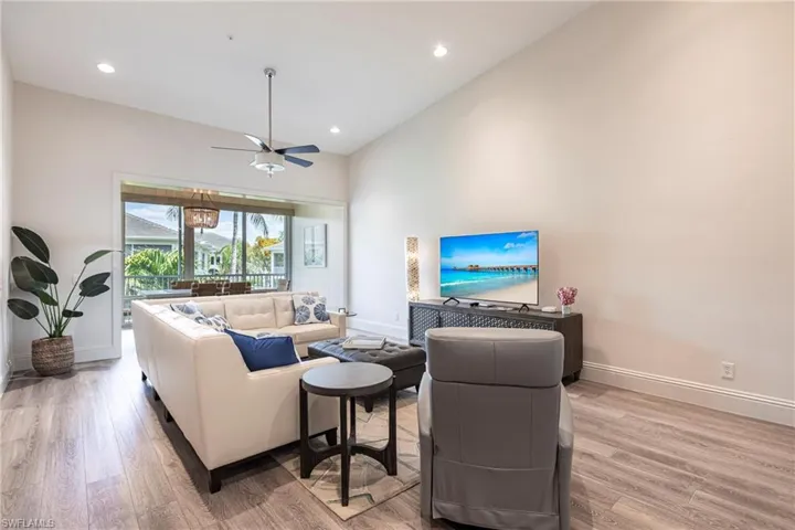 Living area with ceiling fan, light wood-style floors, high vaulted ceiling, and baseboards