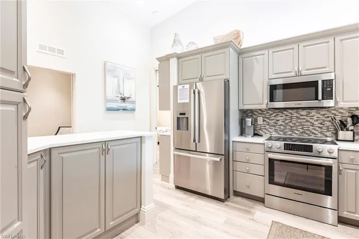 Kitchen with gray cabinets, visible vents, appliances with stainless steel finishes, and light countertops