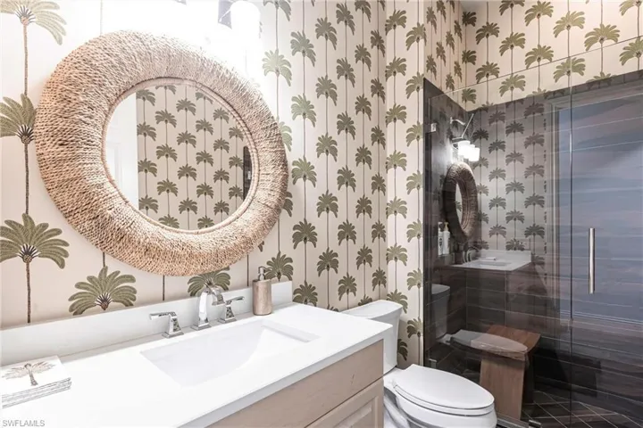 Full bath with wallpapered walls, a shower stall, toilet, and vanity