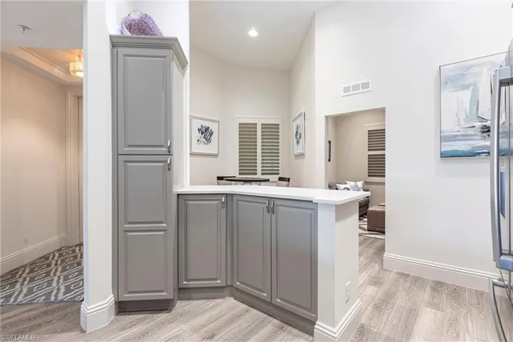Kitchen with gray cabinetry, light wood finished floors, visible vents, and a peninsula