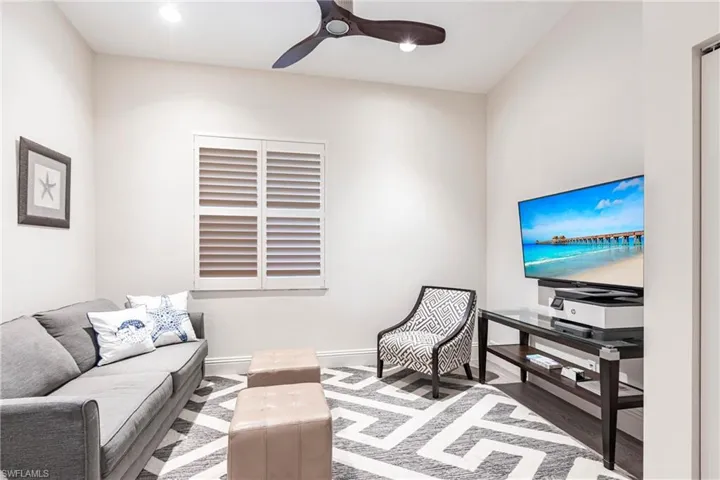 Living area with a ceiling fan, wood finished floors, and baseboards