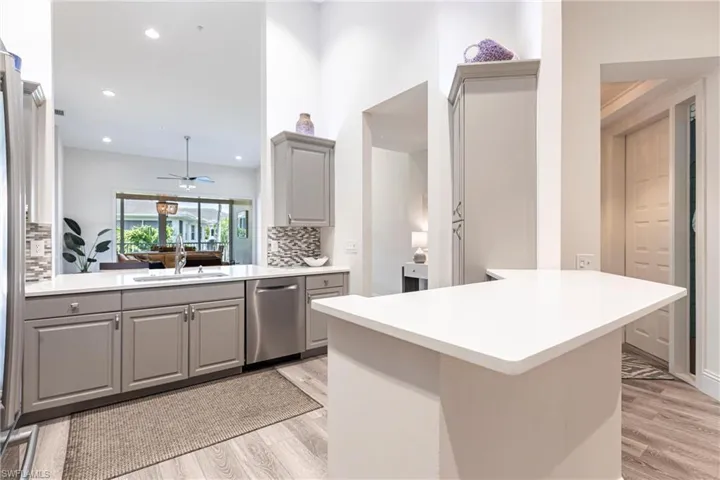 Kitchen featuring light wood finished floors, a sink, backsplash, gray cabinetry, and dishwasher