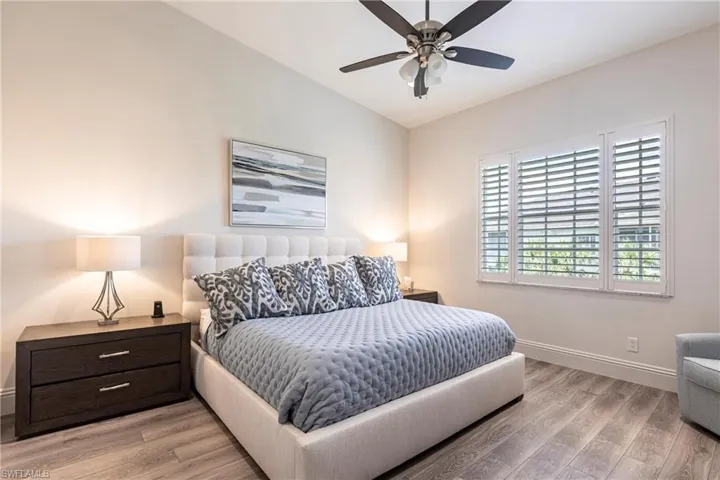 Bedroom featuring light wood-type flooring, a ceiling fan, vaulted ceiling, and baseboards