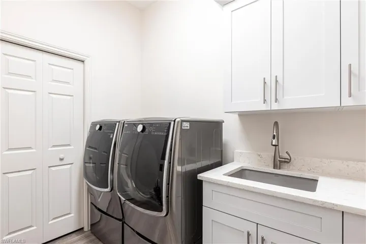Laundry area featuring a sink, cabinet space, and washing machine and dryer