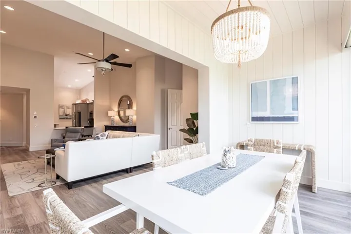 Dining space with ceiling fan with notable chandelier, light wood finished floors, and baseboards