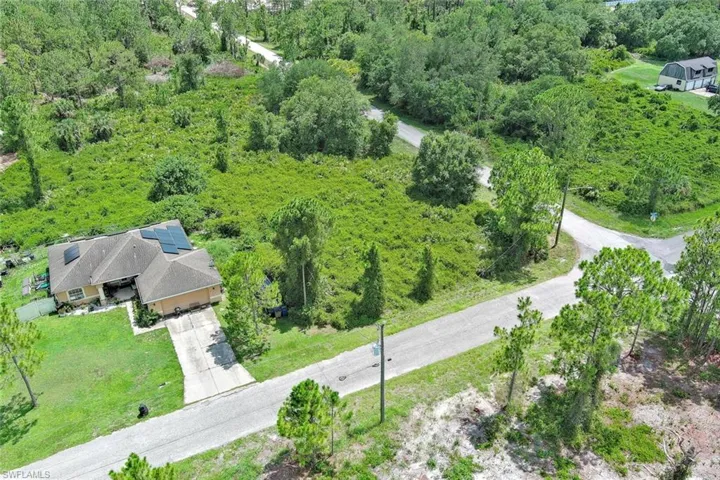 Aerial view of property and surrounding area with a forest