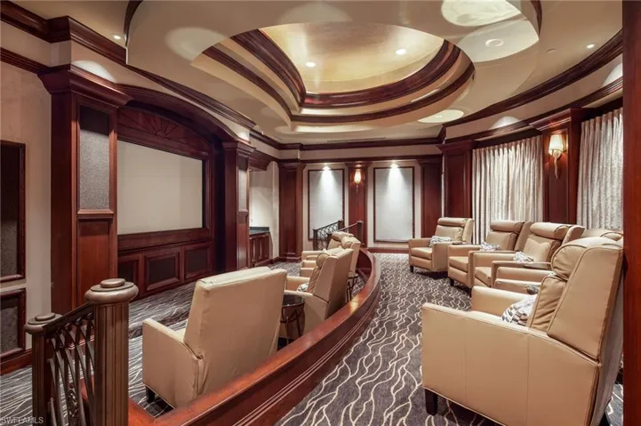 Home theater featuring a raised ceiling, a decorative wall, ornamental molding, and dark carpet