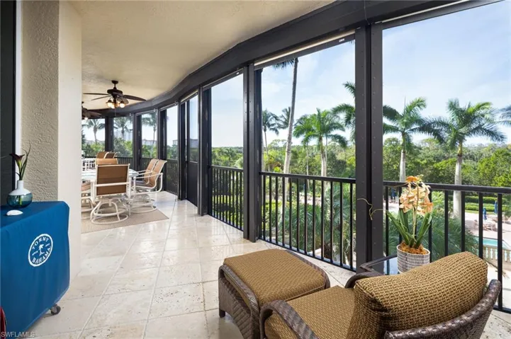 Sunroom with a wall of windows, stone tile flooring, a textured wall, and a textured ceiling