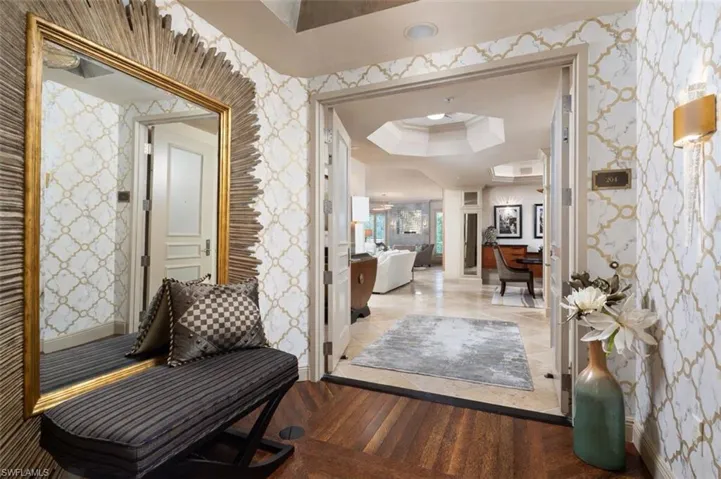 Hall featuring wallpapered walls, wood finished floors, and a tray ceiling