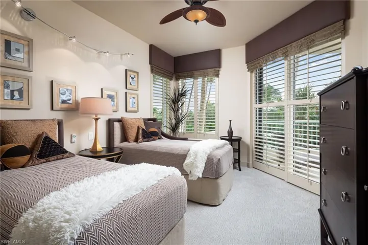 Carpeted bedroom with multiple windows and ceiling fan