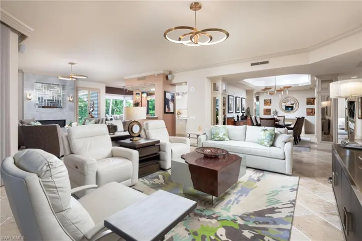 Living area featuring a chandelier, ornamental molding, a fireplace, and a raised ceiling