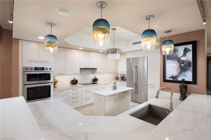 Kitchen featuring stainless steel appliances, decorative light fixtures, white cabinetry, decorative backsplash, and a kitchen island