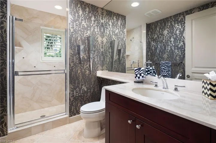 Bathroom with vanity, wallpapered walls, a stall shower, and light tile patterned floors