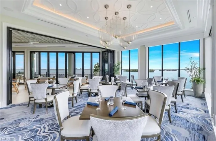 Dining space with a tray ceiling, a water view, a chandelier, ornamental molding, and carpet flooring