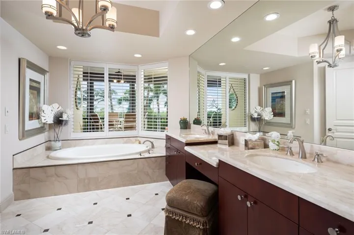 Bathroom featuring a chandelier, double vanity, a garden tub, healthy amount of natural light, and recessed lighting
