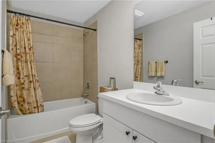 Bathroom with vanity, shower / bath combo with shower curtain, and tile patterned flooring