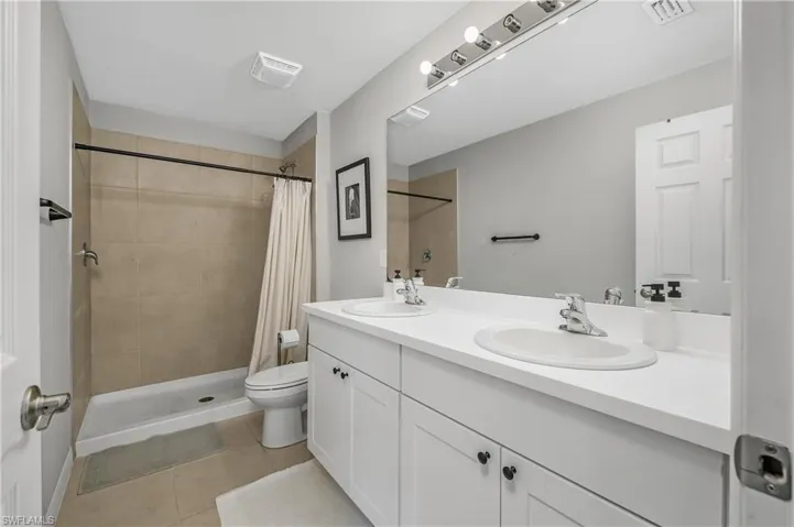 Full bathroom with a shower stall, double vanity, and light tile patterned flooring