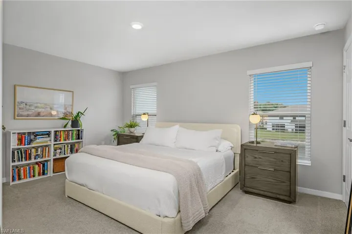 Bedroom featuring light carpet and multiple windows
