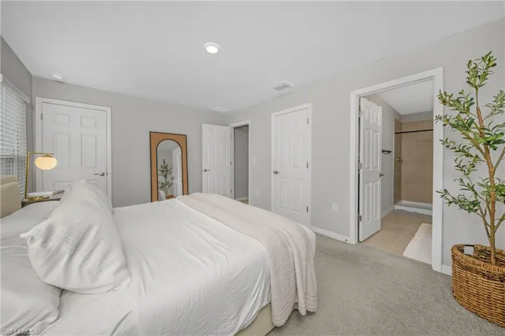 Bedroom featuring light colored carpet and ensuite bath
