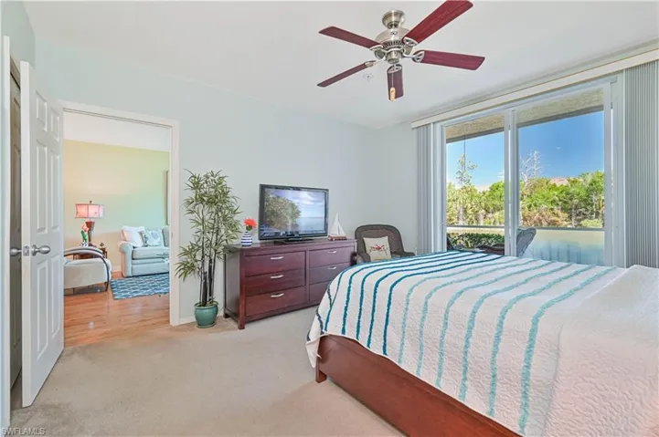 Bedroom featuring light carpet and ceiling fan.  Floor to ceiling sliders to the huge lanai.