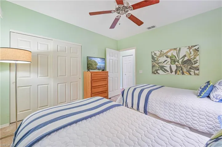 Bedroom with a ceiling fan, a closet, and light carpet, and the suite has pocket doors for privacy.