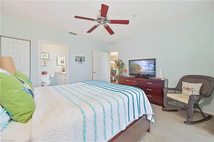 Bedroom with ceiling fan, light carpet, a walk in closet, and ensuite bath