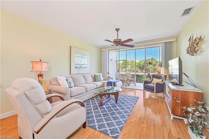 Living room featuring ceiling fan, light wood-style flooring, and baseboards