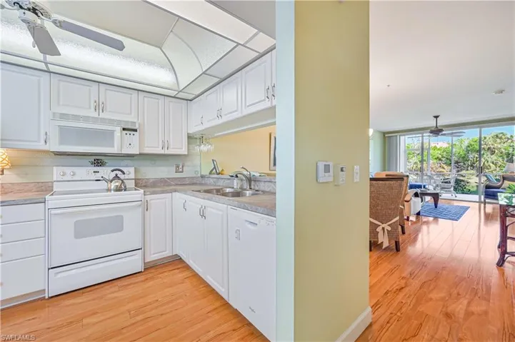 Kitchen featuring light wood finished floors, white appliances, a sink, and white cabinetry