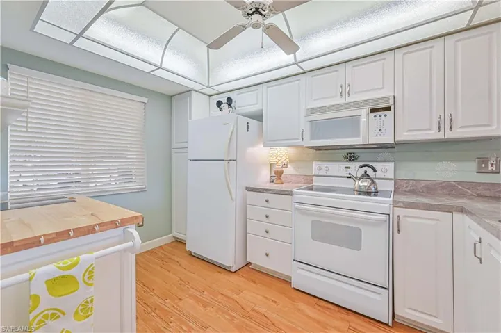 Kitchen featuring light wood-type flooring, white appliances, white cabinets, a ceiling fan, and extra work space.
