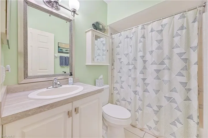 Bathroom featuring toilet, tile patterned flooring, a shower with shower curtain, and vanity