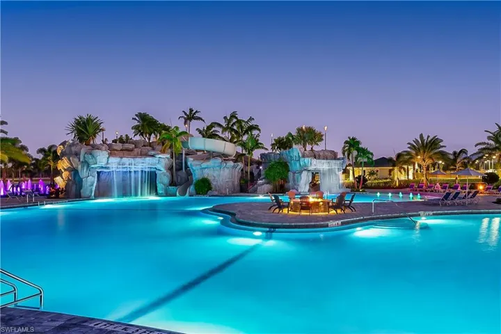 Community Pool at dusk featuring a water slide and pool water feature