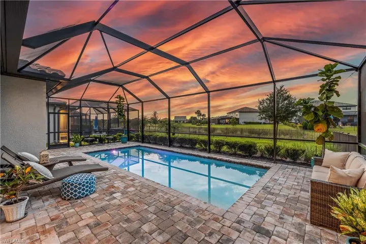 Pool at dusk featuring a patio area and glass enclosure