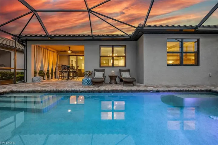 Pool at dusk featuring a lanai, a patio, and ceiling fan