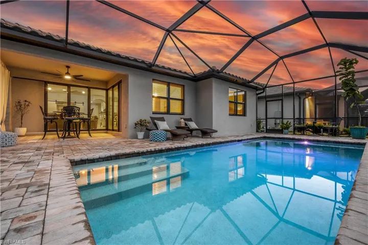 Pool at dusk with ceiling fan, a patio area, and a lanai