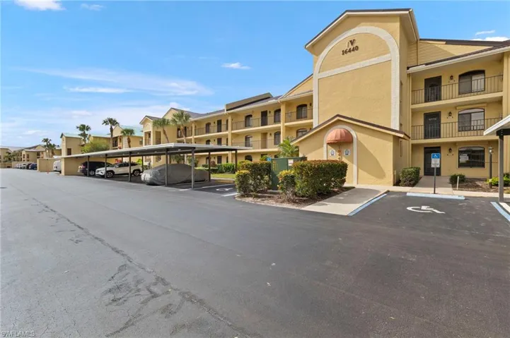 View of apartment building / complex featuring covered and uncovered parking