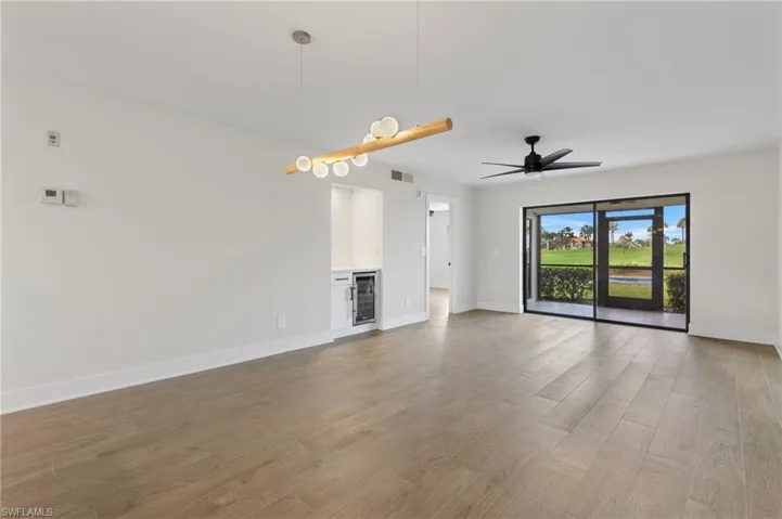 Unfurnished living room with light wood-type flooring, ceiling fan, and beverage cooler